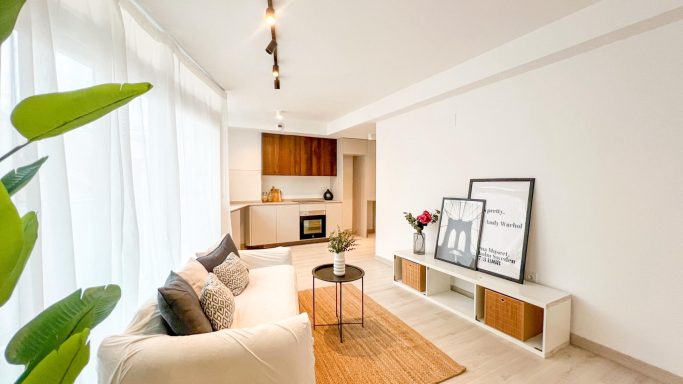 Sala de estar moderna con sofá claro, mesa de centro y decoración minimalista.