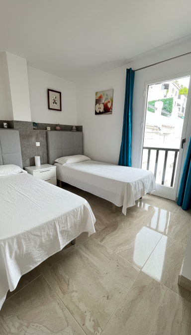 Habitación luminosa con dos camas individuales y ventana con cortinas azules.