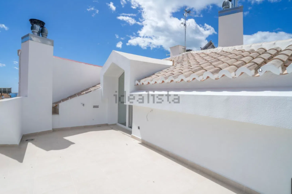 Terraza Terraza moderna con suelo claro y paredes blancas, bajo un cielo azul con nubes.